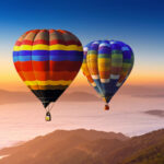Landscape of morning fog and mountains with hot air balloons at sunrise.
